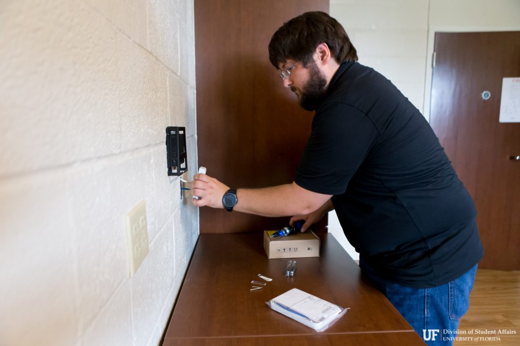 Alex Grover, UFSA IT, installs a wireless access point within a resident's room.